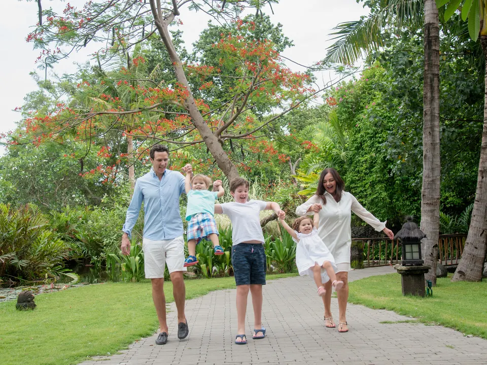 Parents and three children sharing a playful moment in a tropical garden