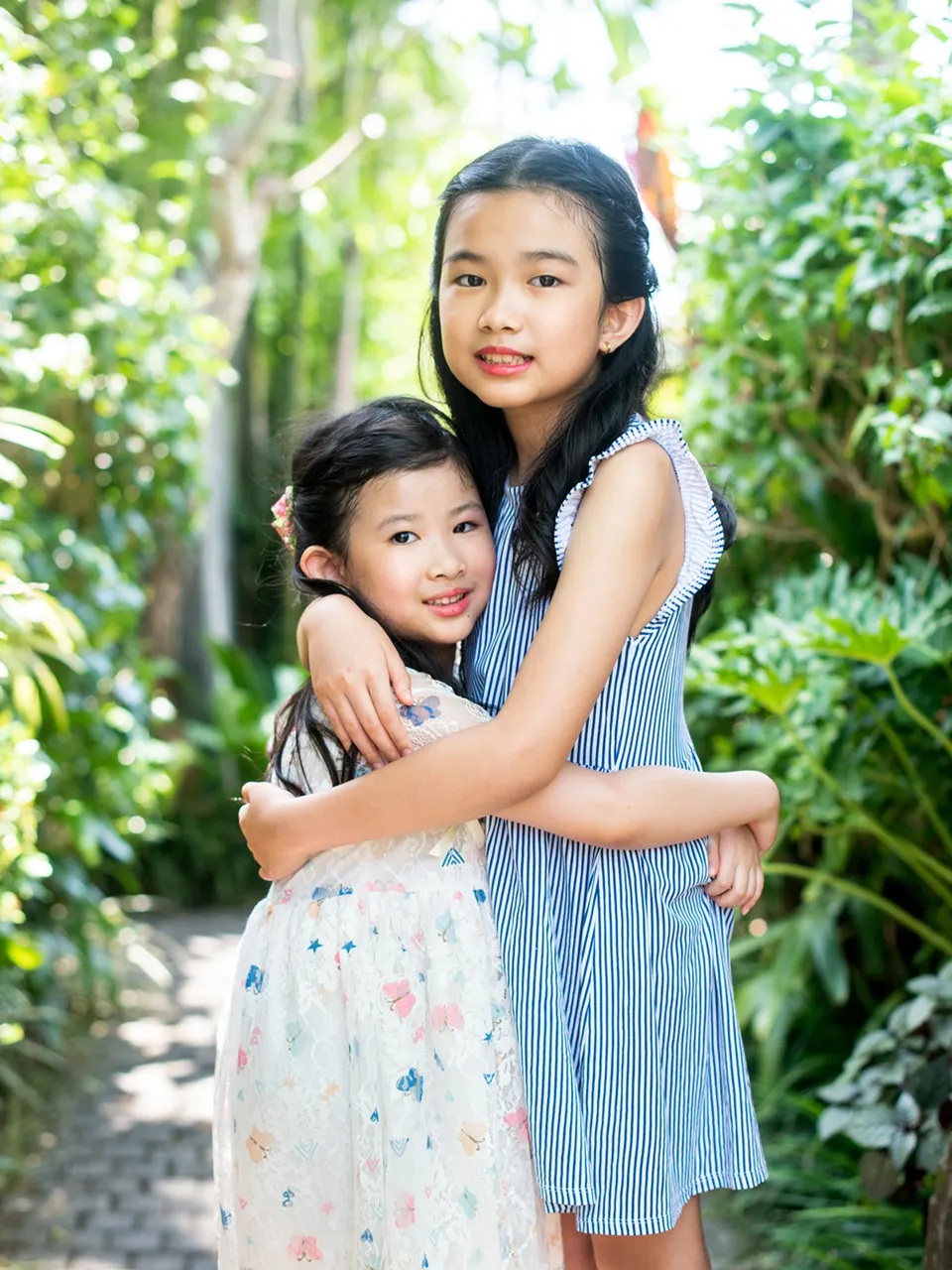 Two sisters embracing among tropical greenery