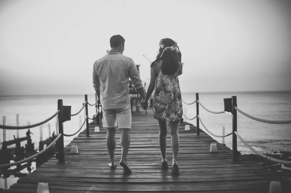 Black-and-white photograph of a couple on a seaside walkway