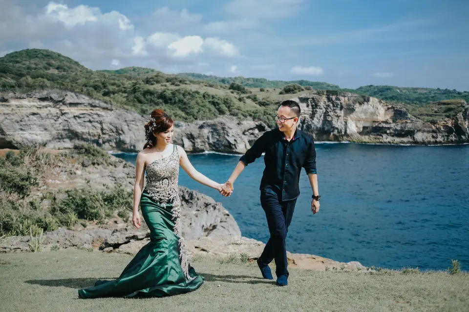 Couple holding hands as they walk along the rocky coast